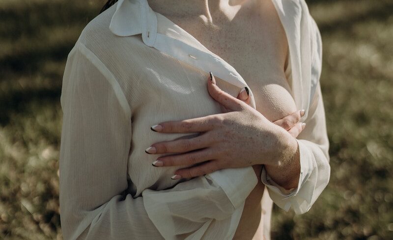 Young Partly Dressed Woman Covering her Breasts with Hands