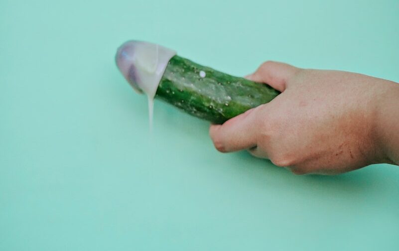 A Person Holding Green Cucumber on Teal Table