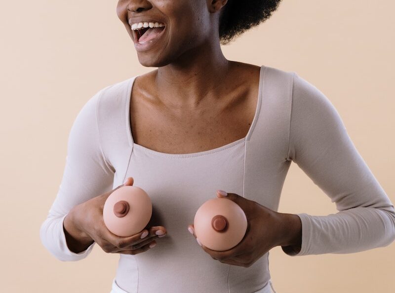 Woman in White Long Sleeve Shirt Holding Breast Like Toys